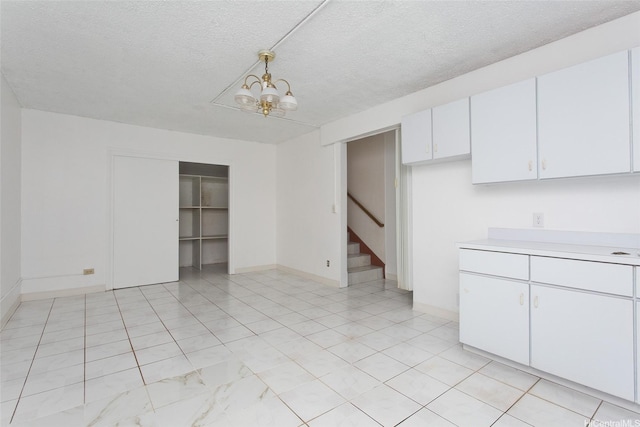98-364 Kaonohi St Unit 11386, Aiea, HI 96701 - kitchen featuring light countertops, a textured ceiling, white cabinetry, a chandelier, and baseboards
