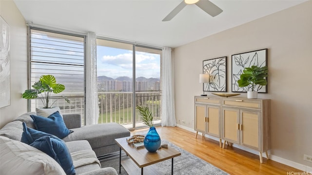 949 Ala Nanala St Unit 1201, Honolulu, HI 96818 - living room featuring light wood-style flooring, ceiling fan, baseboards, and a wall of windows