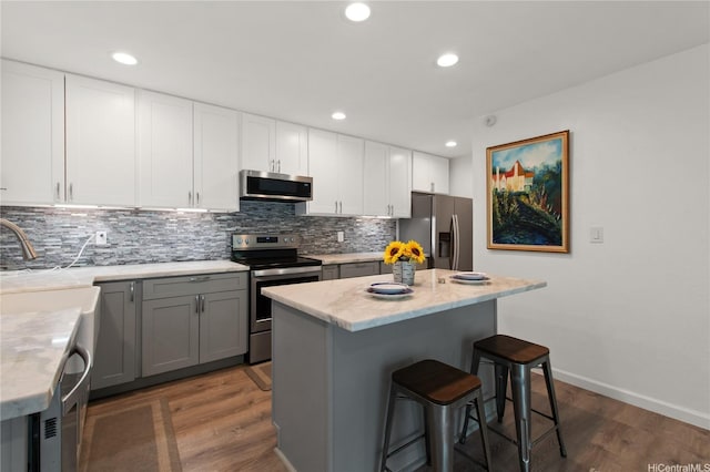 47-730 Hui Kelu St Unit 4404, Kaneohe, HI 96744 - kitchen with appliances with stainless steel finishes, decorative backsplash, wood finished floors, a kitchen breakfast bar, and recessed lighting