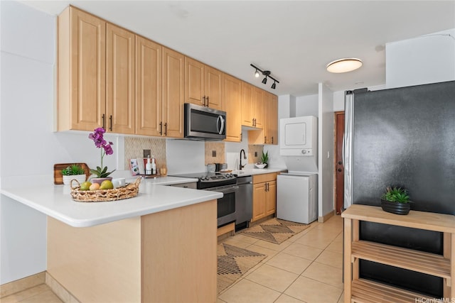 222 Kaiulani Ave Unit Ph3, Honolulu, HI 96815 - kitchen with appliances with stainless steel finishes, estacked washer and dryer, a peninsula, light tile patterned flooring, and light countertops