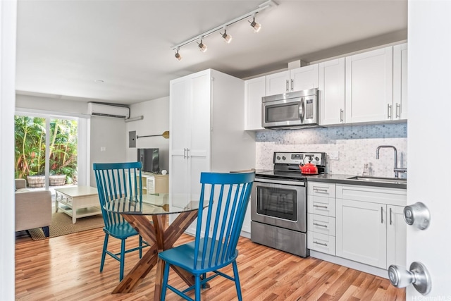 3037 Hinano St, Honolulu, HI 96815 - kitchen with stainless steel appliances, a sink, a wall mounted AC, white cabinets, and dark countertops
