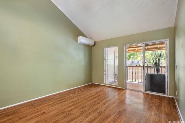 98-1369 Koaheahe Pl Unit 989, Pearl City, HI 96782 - spare room featuring vaulted ceiling, a wall mounted AC, wood finished floors, baseboards, and a textured ceiling