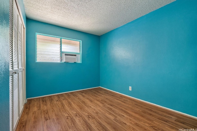 98-1369 Koaheahe Pl Unit 989, Pearl City, HI 96782 - unfurnished room with wood finished floors, a textured ceiling, cooling unit, and baseboards