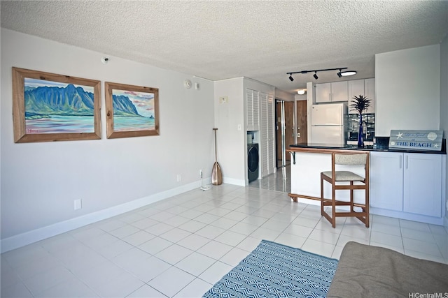 2724 Kahoaloha Ln Unit 902, Honolulu, HI 96826 - kitchen with freestanding refrigerator, washer / dryer, dark countertops, rail lighting, and a textured ceiling