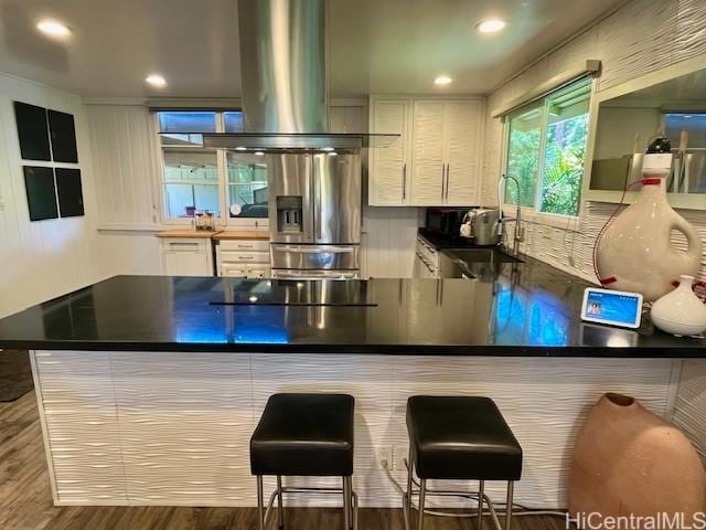 91-1708 Bond St, Ewa Beach, HI 96706 - kitchen with island range hood, stainless steel fridge, wood finished floors, white cabinetry, and recessed lighting