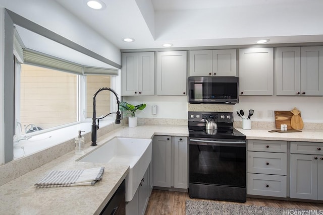 kitchen with black / electric stove, stainless steel microwave, gray cabinetry, wood finished floors, and recessed lighting