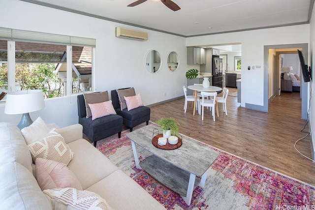 living area featuring a wall mounted AC, ceiling fan, wood finished floors, and ornamental molding