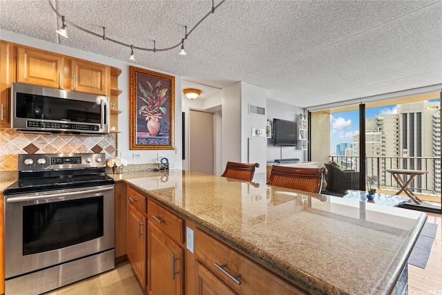411 Hobron Ln Unit 3314, Honolulu, HI 96815 - kitchen with appliances with stainless steel finishes, a peninsula, decorative backsplash, light stone countertops, and brown cabinetry