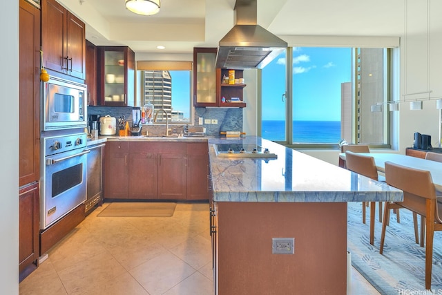 1551 Ala Wai Blvd Unit 2906, Honolulu, HI 96815 - kitchen featuring appliances with stainless steel finishes, wall chimney exhaust hood, a peninsula, decorative backsplash, and glass insert cabinets