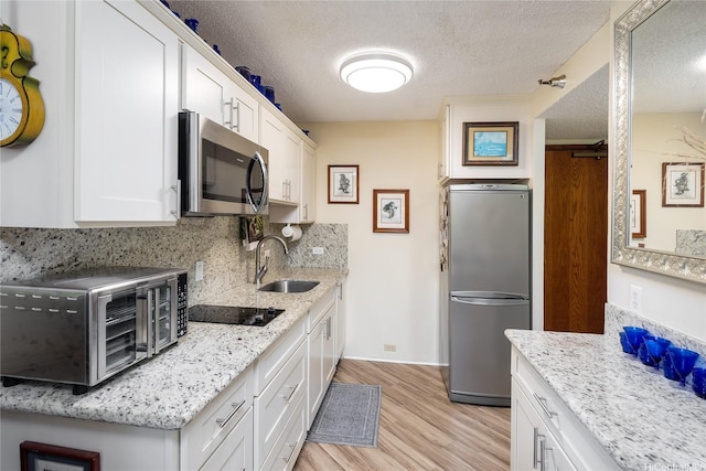 300 Wai Nani Way Unit I304, Honolulu, HI 96815 - kitchen with stainless steel appliances, a sink, light wood finished floors, white cabinets, and a textured ceiling