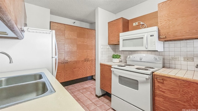 60 N Beretania St Unit 1702, Honolulu, HI 96817 - kitchen featuring white appliances, a sink, brown cabinetry, decorative backsplash, and a textured ceiling