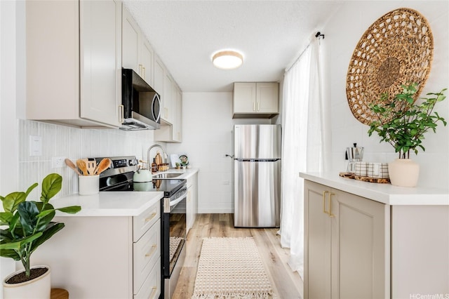 906 Lehua Ave Unit C301, Pearl City, HI 96782 - kitchen featuring appliances with stainless steel finishes, light wood-style floors, light countertops, a sink, and a textured ceiling