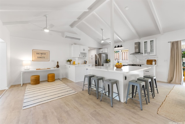 464 Poipu Dr, Honolulu, HI 96825 - kitchen with a ceiling fan, stainless steel refrigerator with ice dispenser, wall chimney range hood, a center island with sink, and a kitchen bar