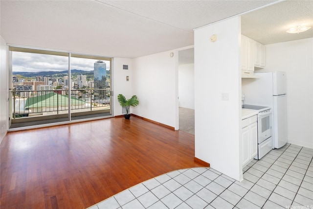 400 Hobron Ln Unit 2412, Honolulu, HI 96815 - kitchen with white range with electric cooktop, under cabinet range hood, light wood-style floors, white cabinets, and light countertops