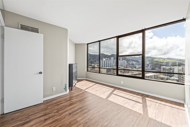 1221 Victoria St Unit 1705, Honolulu, HI 96814 - spare room with a city view, wood finished floors, and baseboards