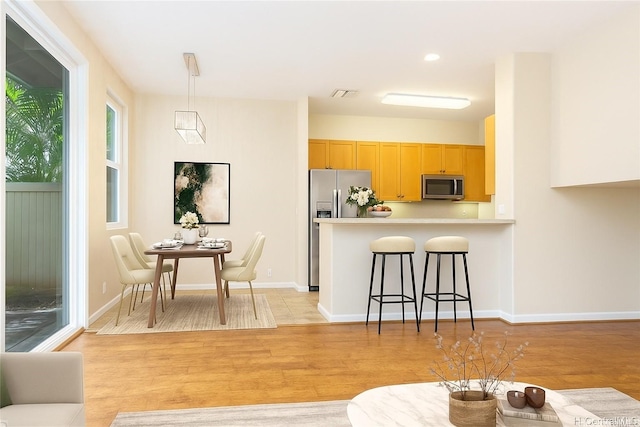 91-1083 Kanela St Unit T22, Ewa Beach, HI 96706 - kitchen with stainless steel appliances, a breakfast bar, light wood-style floors, light brown cabinetry, and light countertops