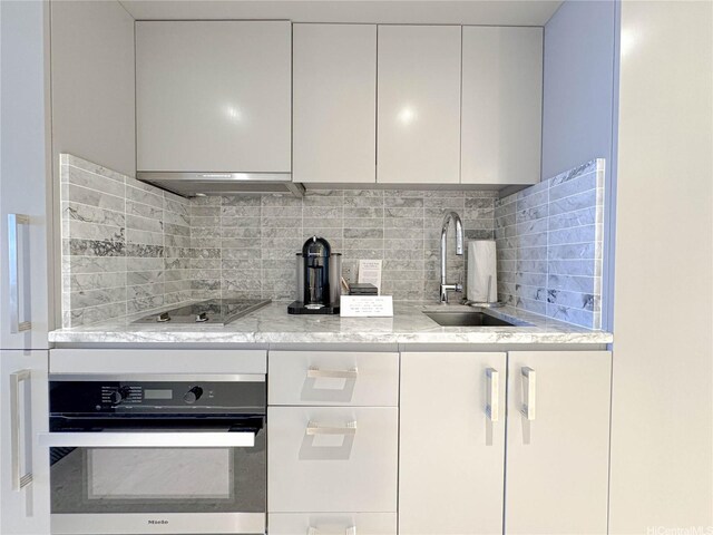 383 Kalaimoku St Unit 1807, Honolulu, HI 96815 - kitchen with oven, electric cooktop, modern cabinets, decorative backsplash, and white cabinets