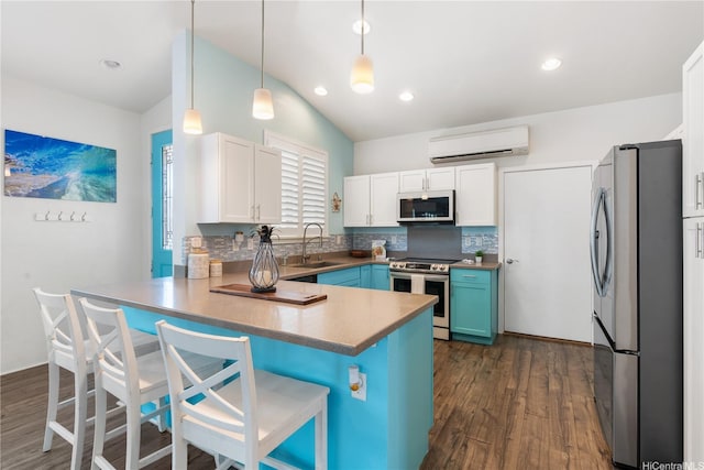 801 Kakala St Unit 50, Kapolei, HI 96707 - kitchen with stainless steel appliances, a wall unit AC, a peninsula, vaulted ceiling, and dark wood finished floors