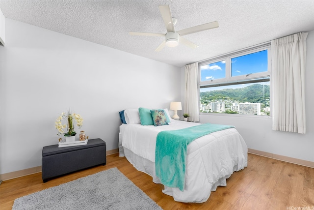 1450 Young St Unit 2004, Honolulu, HI 96814 - bedroom featuring a textured ceiling, wood finished floors, baseboards, and ceiling fan