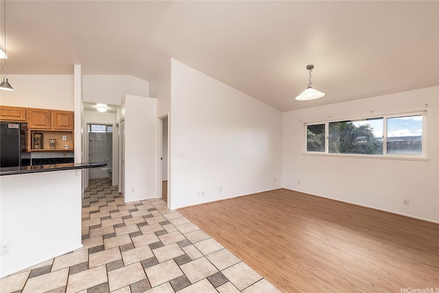 67-374 Haona St, Waialua, HI 96791 - kitchen featuring black fridge, lofted ceiling, pendant lighting, dark countertops, and brown cabinets
