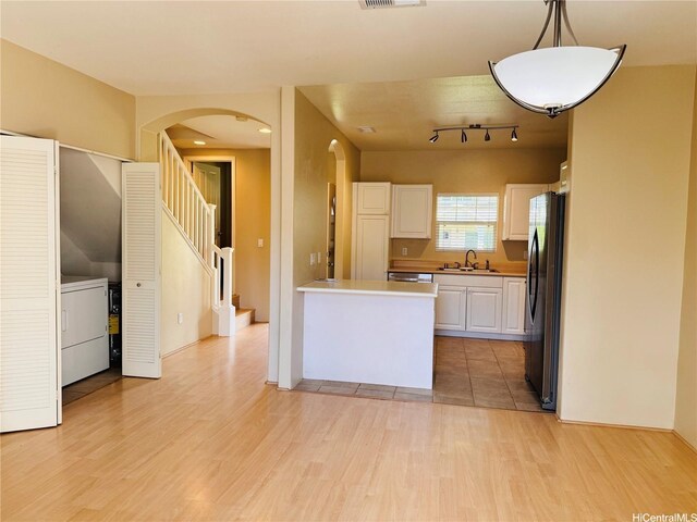 91-1014 Kaipalaoa St Unit 6504, Ewa Beach, HI 96706 - kitchen with freestanding refrigerator, arched walkways, a sink, white cabinetry, and light wood-style flooring