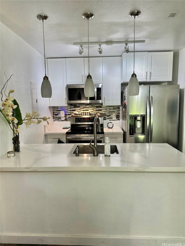 645 Mananai Pl Unit 23Bd, Honolulu, HI 96818 - kitchen featuring appliances with stainless steel finishes, decorative backsplash, a sink, white cabinetry, and a textured ceiling
