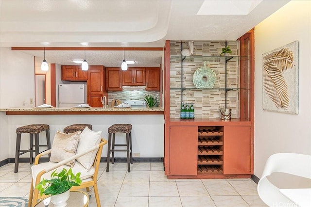 98-380 Koauka Loop Unit 304, Aiea, HI 96701 - bar area featuring freestanding refrigerator, tasteful backsplash, a sink, under cabinet range hood, and light tile patterned floors