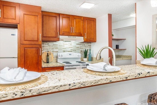 98-380 Koauka Loop Unit 304, Aiea, HI 96701 - kitchen featuring white appliances, under cabinet range hood, backsplash, brown cabinetry, and a textured ceiling