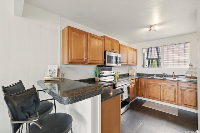 92-956 Makakilo Dr Unit 65, Kapolei, HI 96707 - kitchen with appliances with stainless steel finishes, a sink, a peninsula, a breakfast bar, and brown cabinetry