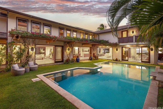 958 Mokulua Dr, Kailua, HI 96734 - rear view of house featuring stucco siding, a yard, an outdoor pool, and a balcony