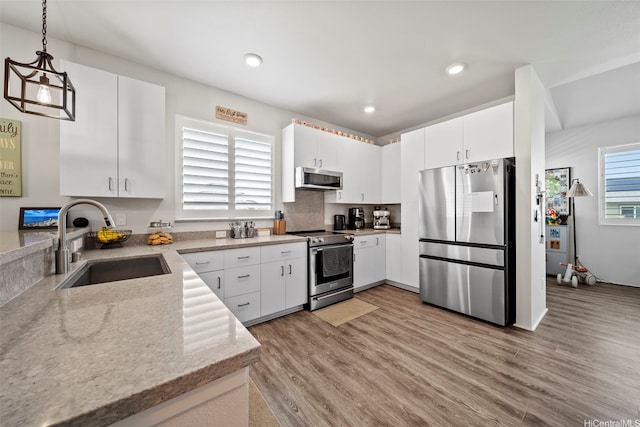 91-1811 Kapeku Loop, Ewa Beach, HI 96706 - kitchen featuring appliances with stainless steel finishes, light wood-style floors, decorative light fixtures, white cabinetry, and light stone counters