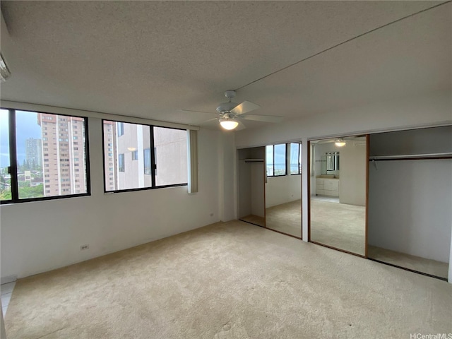 98-501 Koauka Loop Unit A1008, Aiea, HI 96701 - unfurnished bedroom with multiple closets, light colored carpet, a textured ceiling, and a ceiling fan