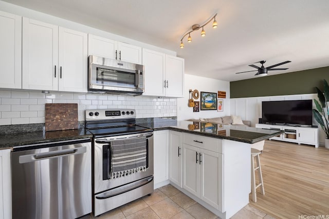 1520 Ward Ave Unit 902, Honolulu, HI 96822 - kitchen featuring appliances with stainless steel finishes, a peninsula, ceiling fan, open floor plan, and white cabinetry
