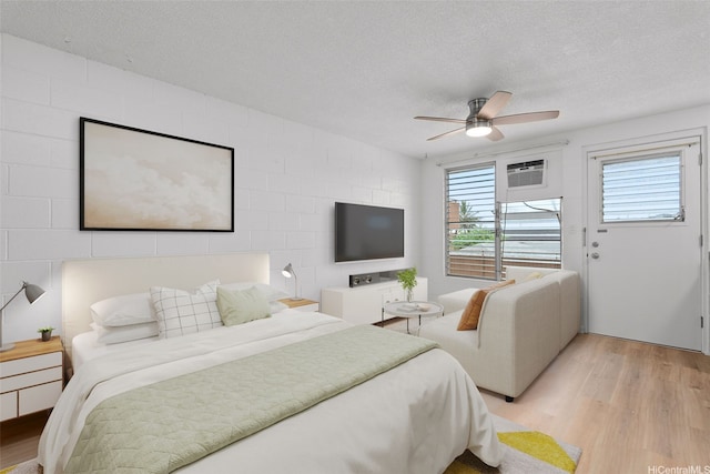 636 Nalanui St Unit 302, Honolulu, HI 96817 - bedroom featuring light wood-style floors, a textured ceiling, a wall mounted air conditioner, and a ceiling fan