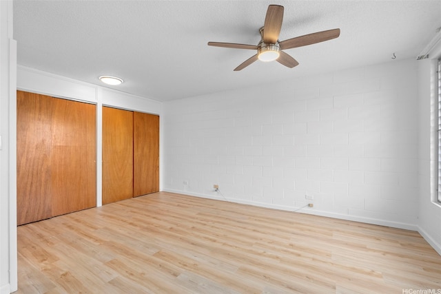 636 Nalanui St Unit 302, Honolulu, HI 96817 - unfurnished bedroom with two closets, concrete block wall, wood finished floors, a textured ceiling, and ceiling fan