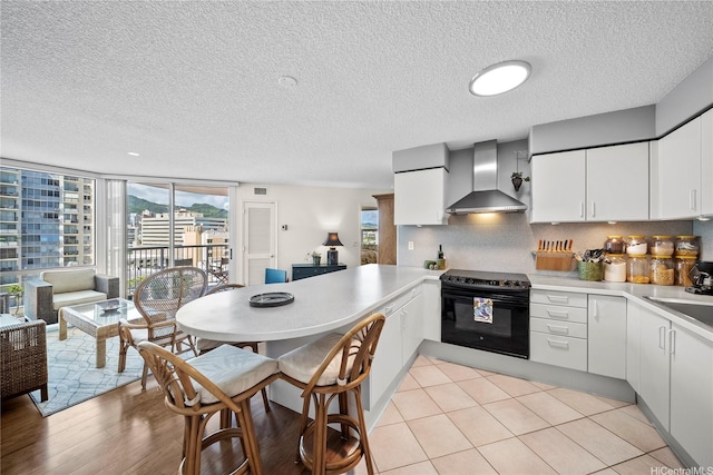 801 S King St Unit 1109, Honolulu, HI 96813 - kitchen with wall chimney range hood, electric range oven, light countertops, a peninsula, and plenty of natural light