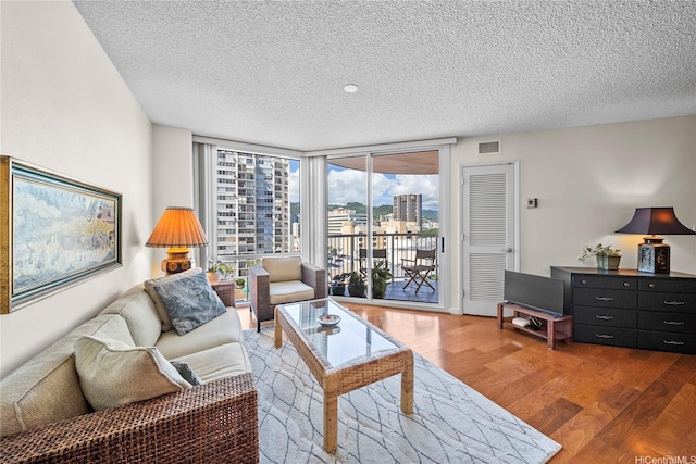 801 S King St Unit 1109, Honolulu, HI 96813 - living area featuring wood finished floors, a textured ceiling, and a wall of windows