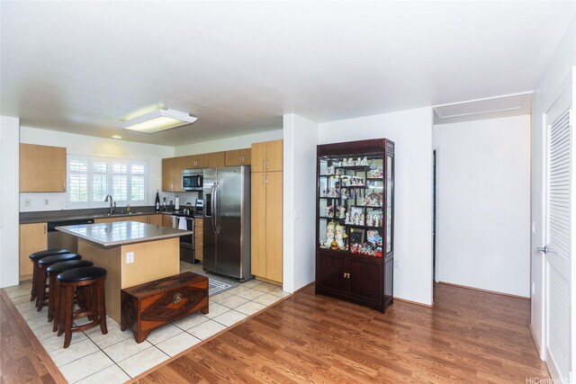 95-955 Ukuwai St Unit 1703, Mililani, HI 96789 - kitchen with appliances with stainless steel finishes, a sink, a kitchen island, dark countertops, and light wood finished floors
