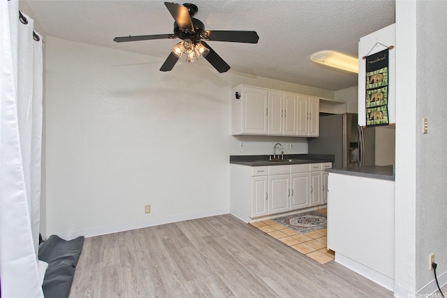 94-1045 Paha Pl Unit T3, Waipahu, HI 96797 - kitchen featuring dark countertops, a sink, white cabinetry, light wood-type flooring, and ceiling fan