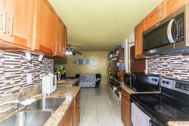 1260 Richard Ln Unit B601, Honolulu, HI 96819 - kitchen featuring stainless steel appliances, decorative backsplash, brown cabinetry, a sink, and a textured ceiling