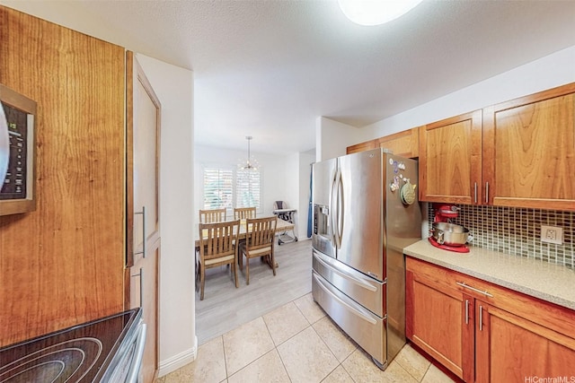 91-215 Keonekapu Pl, Ewa Beach, HI 96706 - kitchen featuring stainless steel refrigerator with ice dispenser, light countertops, brown cabinets, a chandelier, and backsplash