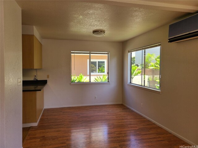 2317 Lime St Unit 2317, Honolulu, HI 96826 - unfurnished dining area featuring a wall mounted AC, dark wood-type flooring, baseboards, and a textured ceiling