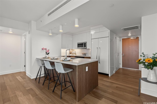 629 Keeaumoku St Unit 2912, Honolulu, HI 96814 - kitchen with stainless steel microwave, modern cabinets, a sink, built in fridge, and a kitchen breakfast bar