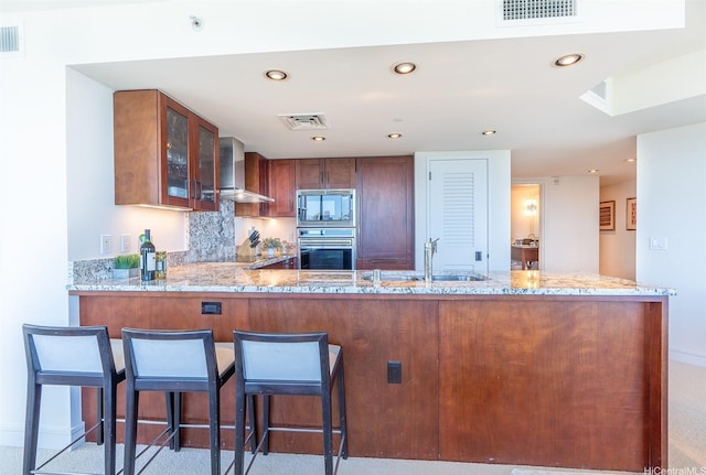 223 Saratoga Rd Unit 2203, Honolulu, HI 96815 - kitchen featuring wall chimney range hood, stainless steel appliances, glass insert cabinets, a peninsula, and light stone counters