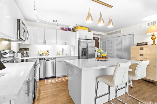 888 Kapiolani Blvd Unit 1512, Honolulu, HI 96813 - kitchen with appliances with stainless steel finishes, a sink, light wood-type flooring, a breakfast bar area, and light countertops