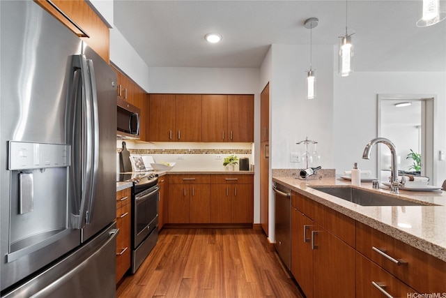 555 S St Unit 3003, Honolulu, HI 96813 - kitchen with stainless steel appliances, brown cabinetry, light wood-style floors, light stone countertops, and decorative light fixtures