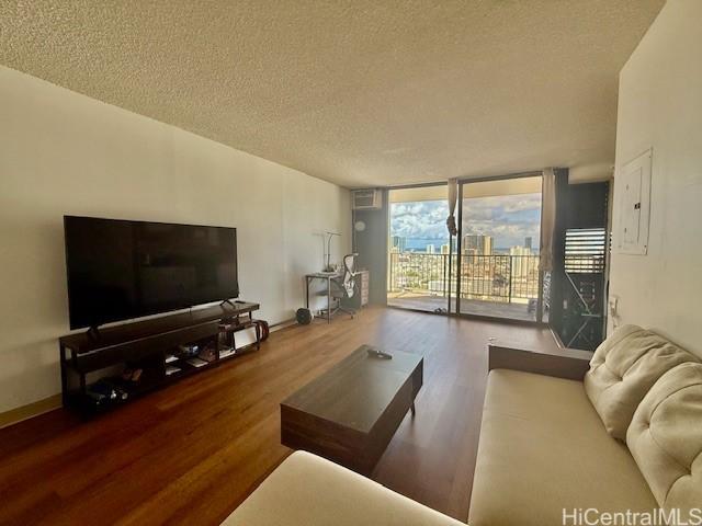 1630 Liholiho St Unit 2001, Honolulu, HI 96822 - living area with wood finished floors, a textured ceiling, a wall of windows, baseboards, and electric panel