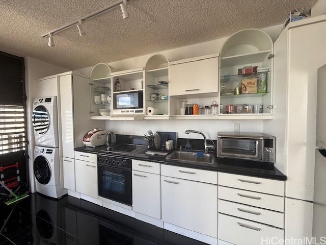 1630 Liholiho St Unit 2001, Honolulu, HI 96822 - kitchen featuring black appliances, stacked washer / drying machine, rail lighting, a sink, and open shelves
