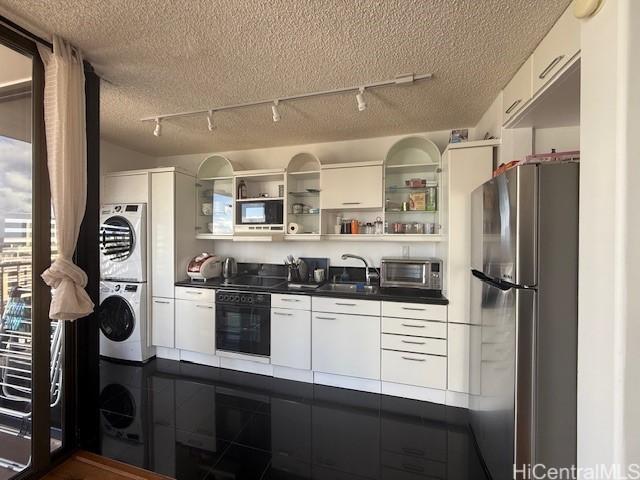 1630 Liholiho St Unit 2001, Honolulu, HI 96822 - kitchen with stacked washer / drying machine, freestanding refrigerator, black oven, rail lighting, and a textured ceiling