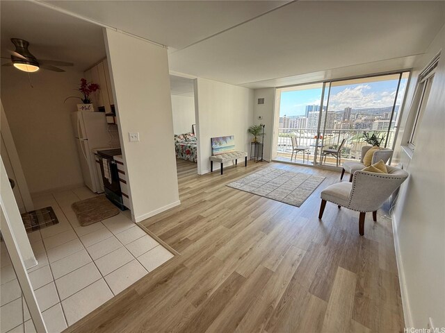 400 Hobron Ln Unit 2114, Honolulu, HI 96815 - living room featuring light wood-type flooring, ceiling fan, expansive windows, a city view, and baseboards